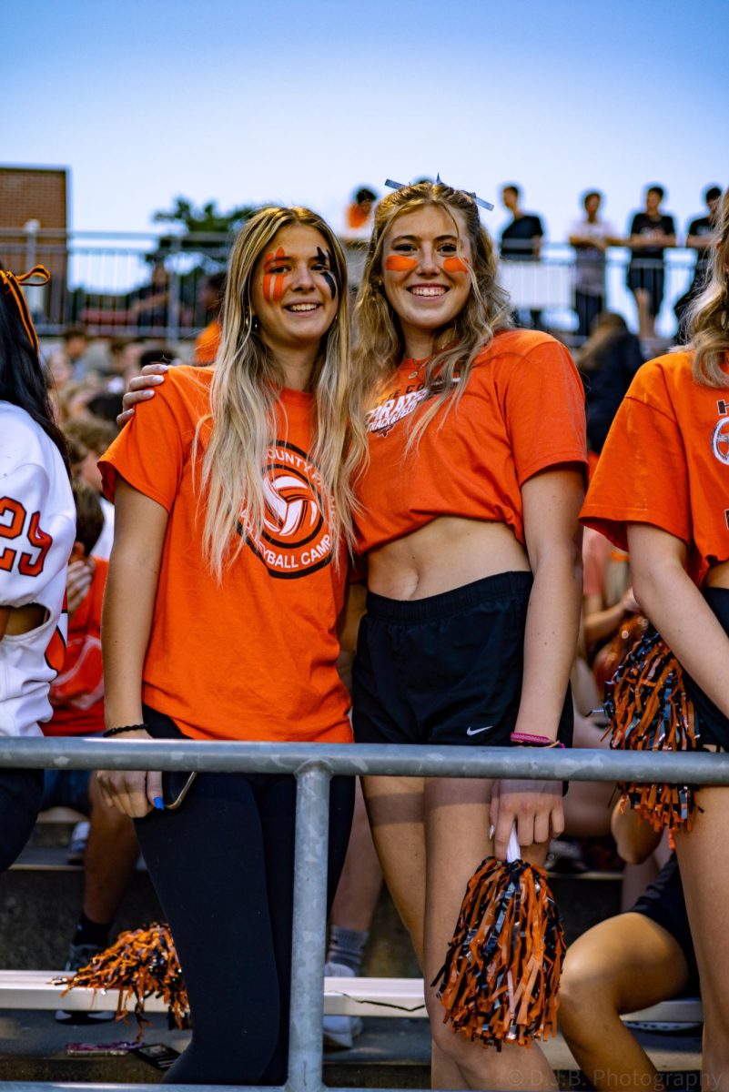 Senior Addyson Schlake and sophomore Allie Riggs pose for a photo in the stands 