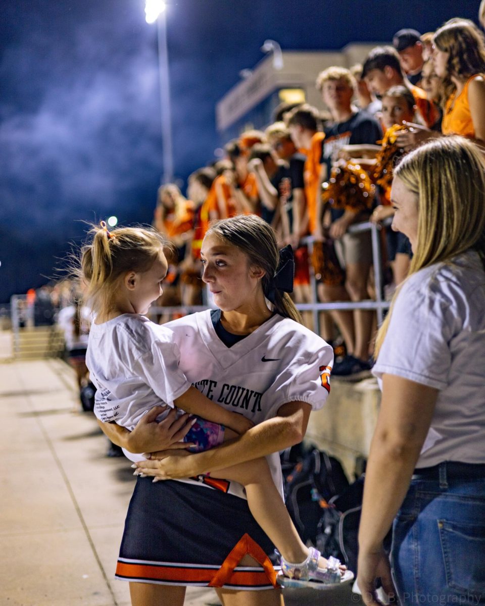 Junior Kinsley Acker holds a small kid 