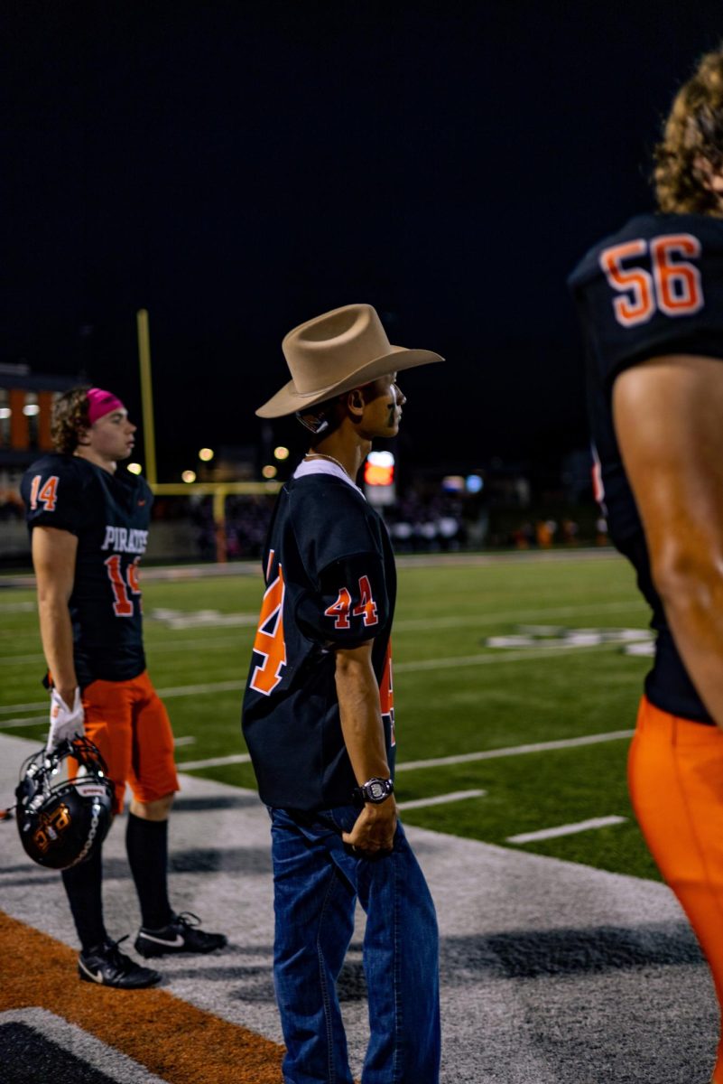 Football Manager senior Eli Cook stands on the sideline watches the game 