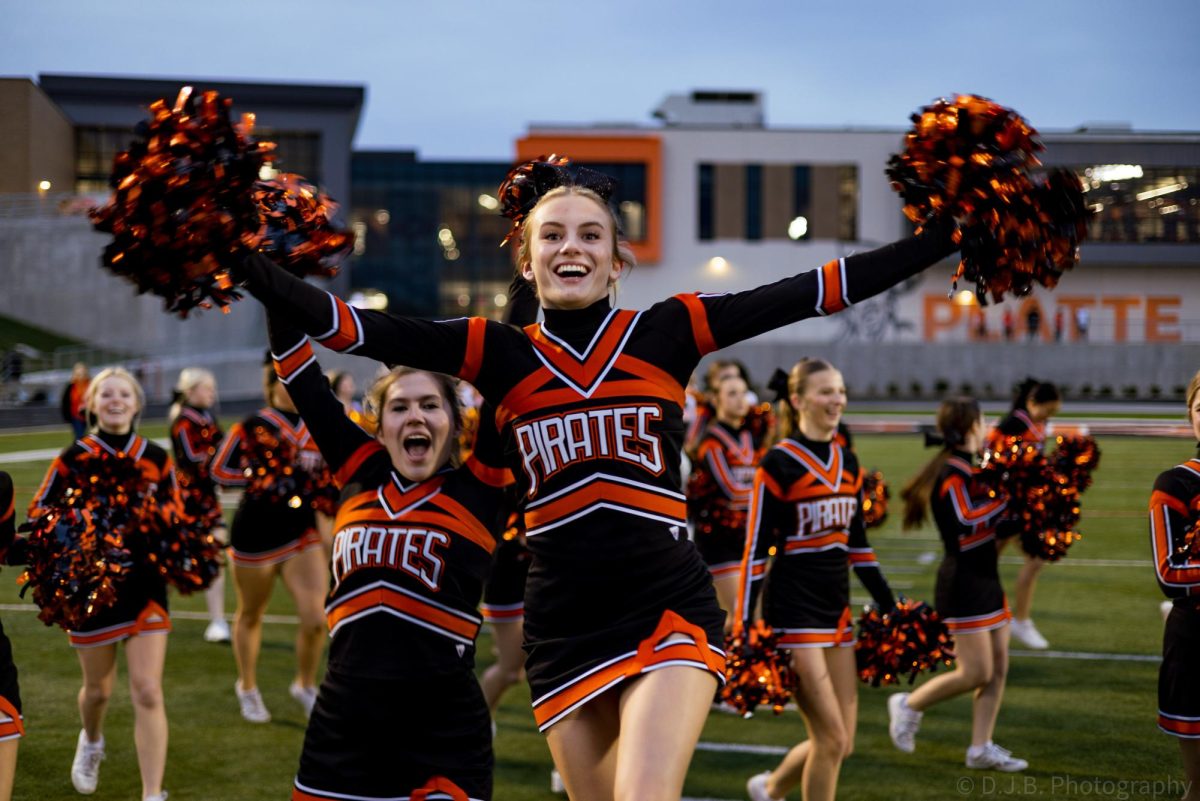 Junior Saylor Lembke jumps in front of camera for a photo while she runs on the field 