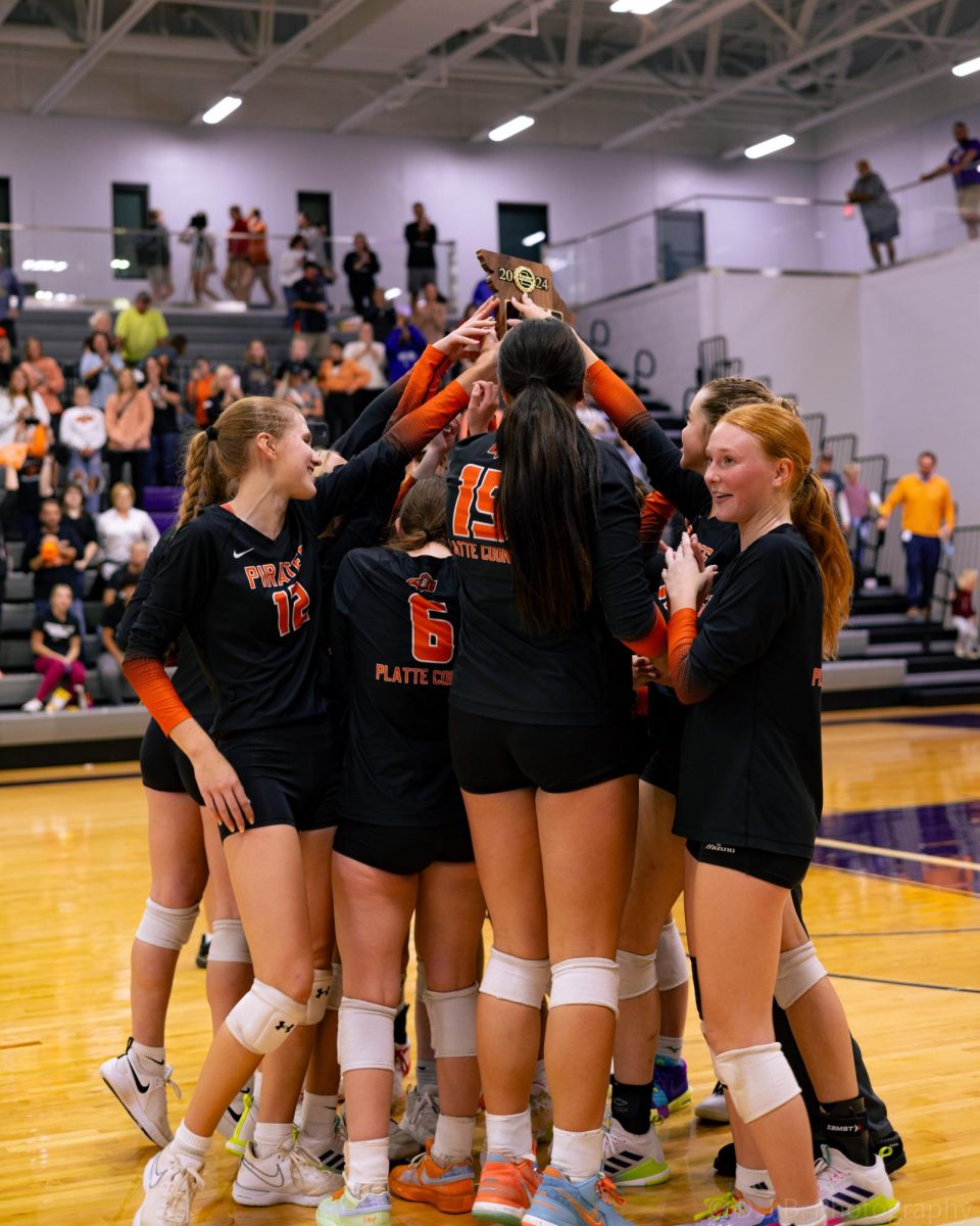 The Volleyball team holds up their district champions trophy after a winning the game 