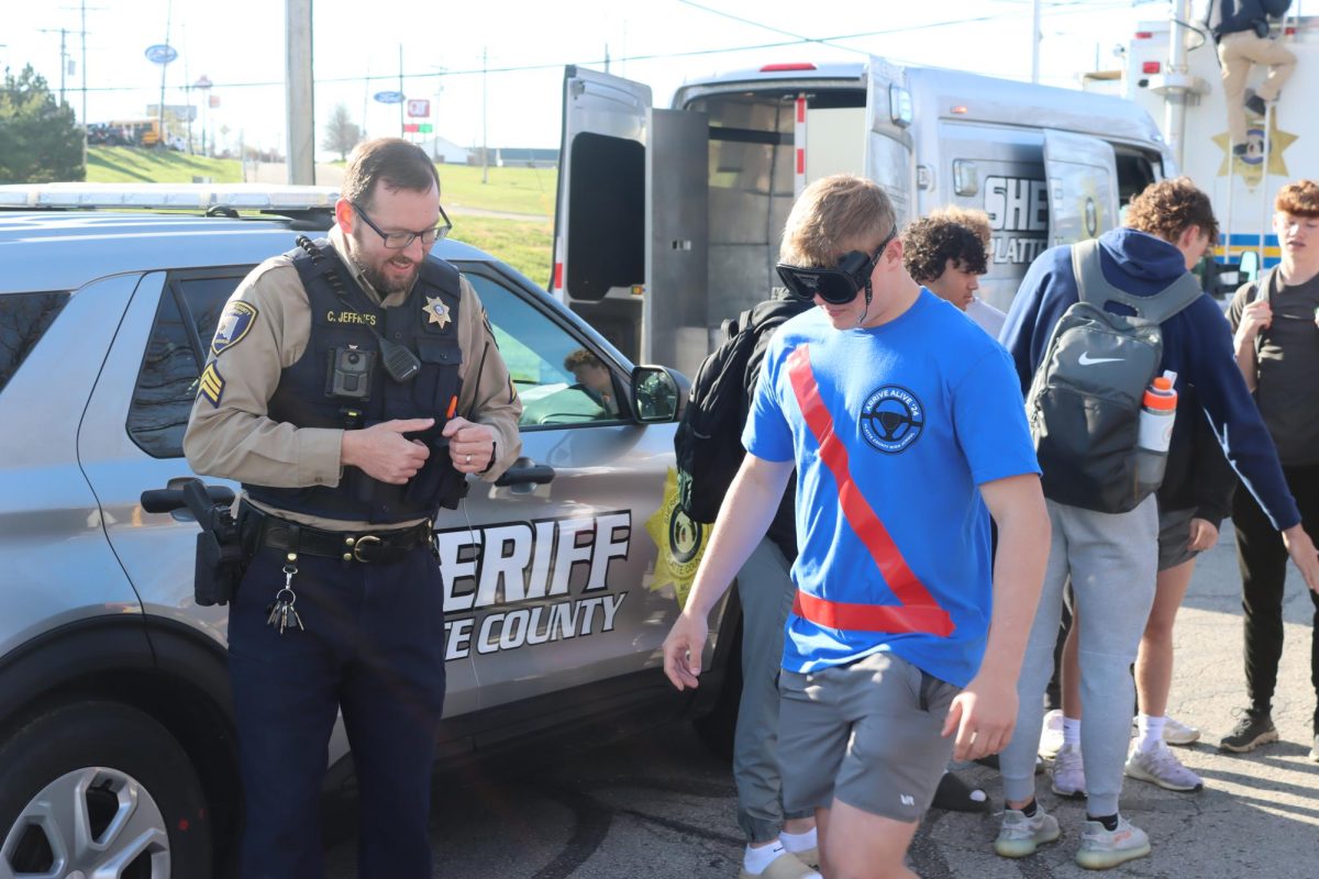 Student wears drunk googles with supervision of a police officer during 2024 Arrive Alive. 